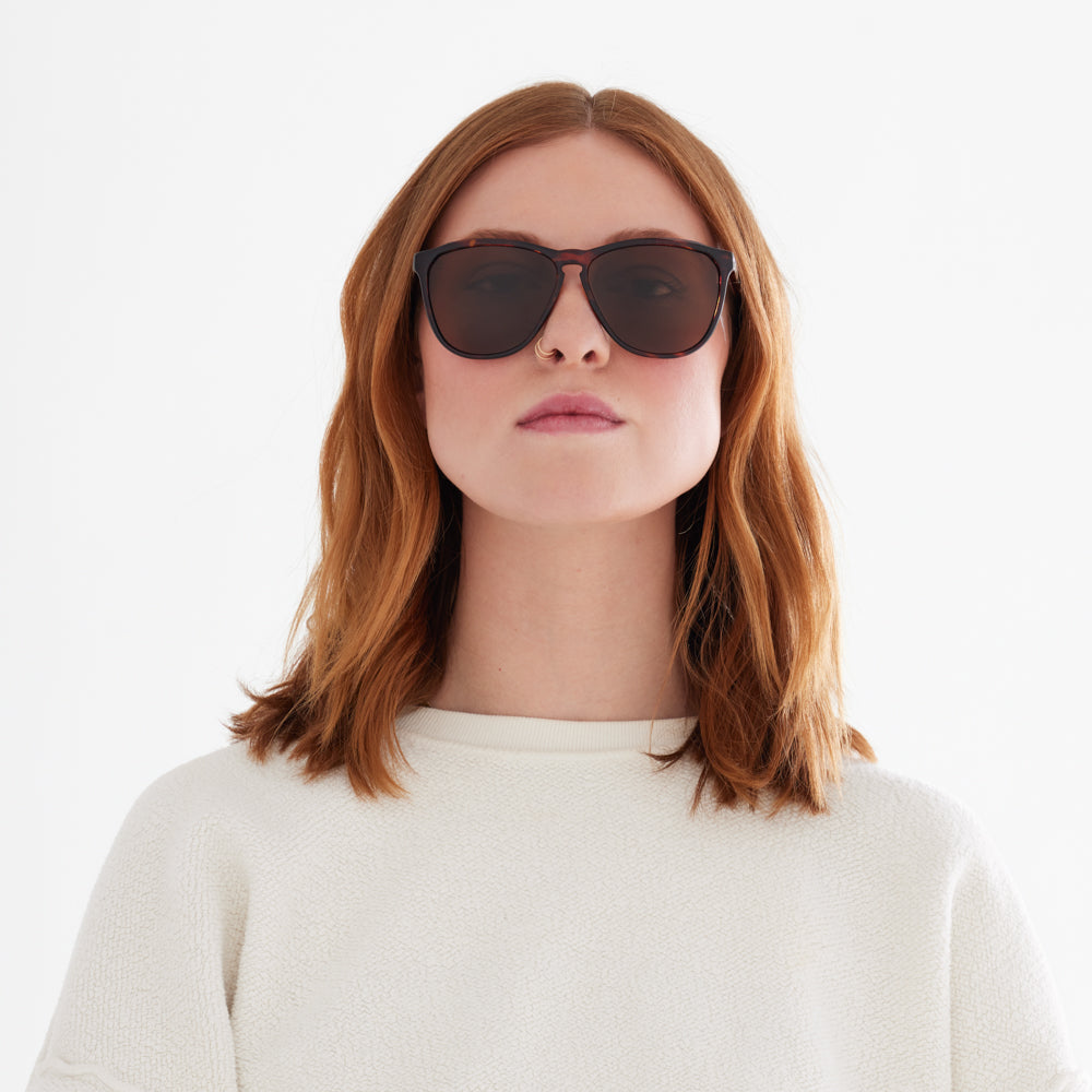 Woman wearing the Tortoise Encelia sunglass frame. Large, rounded shape with bronze polarized lenses 